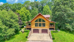 A two-story log cabin with a porch, a satellite dish, and a stone pathway leading to the entrance. - Waters Edge, Cozy Cabin & Pond (Creola)