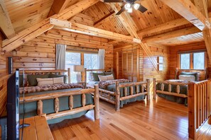 A log cabin interior with a loft bed, a sofa, and a dining table. - Waters Edge, Cozy Cabin & Pond (Creola)