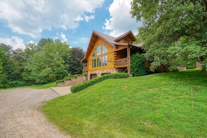 A log cabin with a stone foundation, a stone staircase, and a wooden deck. - Waters Edge, Cozy Cabin & Pond (Creola)
