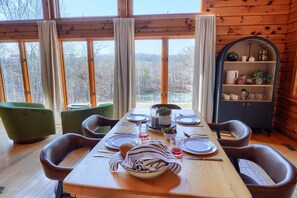 Comedor con mesa de madera para cuatro, sillas, una mesita auxiliar y un armario con utensilios de cocina.