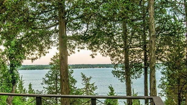 A wooden deck with a view of a lake and trees.