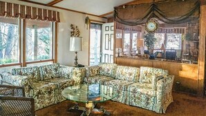 A living room with a sectional sofa, a glass coffee table, and a clock on the wall.