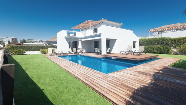 Une maison moderne dotée d’une piscine, d’une terrasse en bois et d’une pelouse bien entretenue.