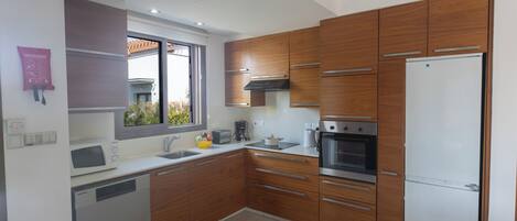 A modern kitchen with wooden cabinets, stainless steel appliances, and a built-in oven.