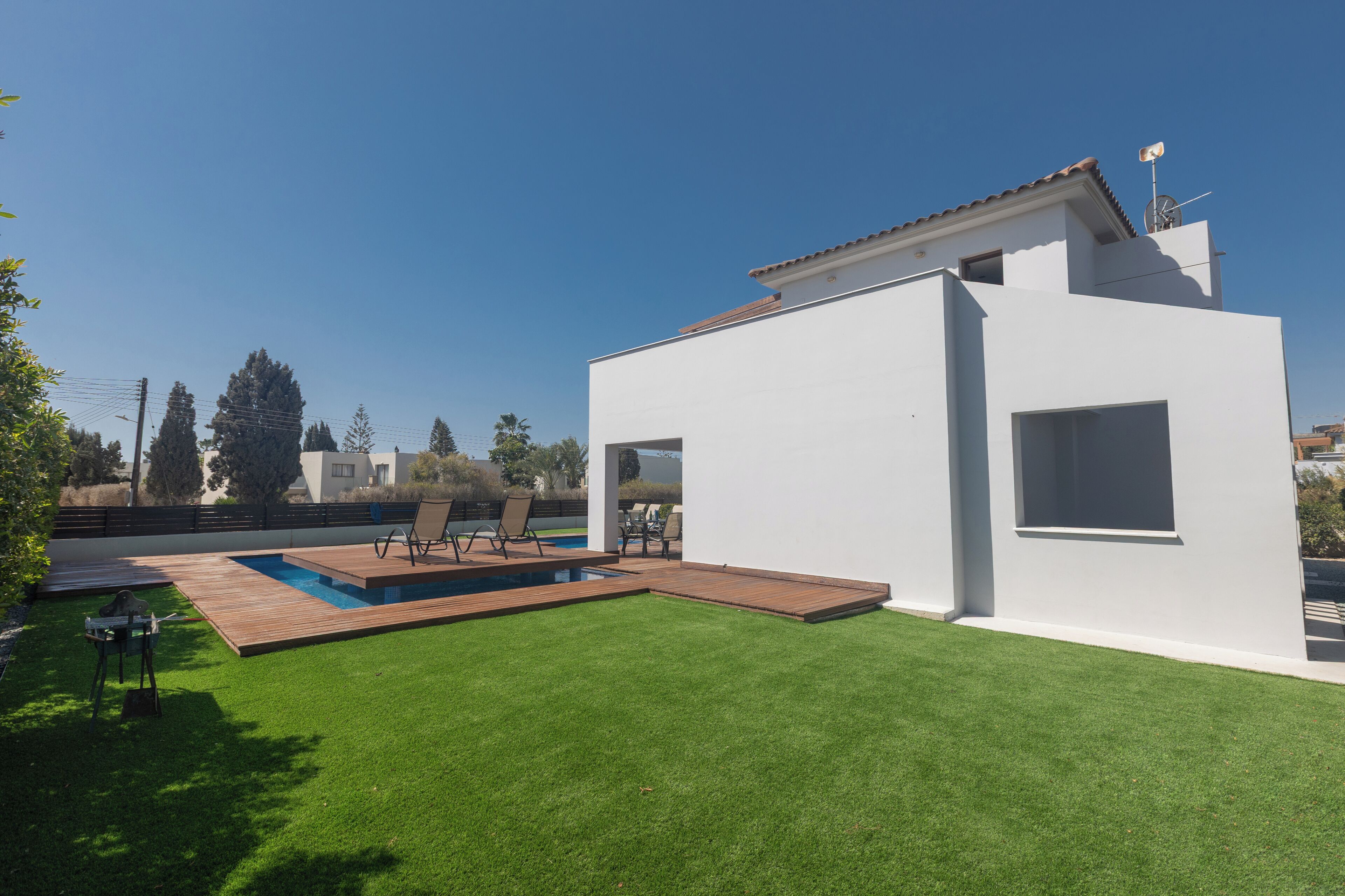 Une maison moderne dotée d’une piscine, d’un patio et d’une pelouse bien entretenue.