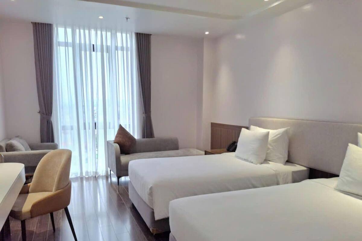 A hotel room with two beds, a sofa, a chair, and a desk.