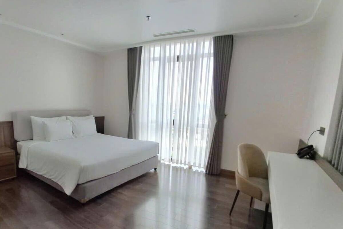 A hotel room with a bed, a desk, and a chair.