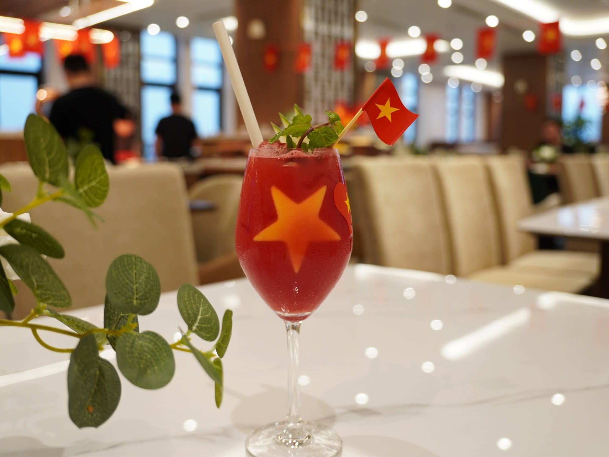 Un vaso de bebida roja con una decoración de estrella y una bandera, colocado sobre una mesa en un restaurante.