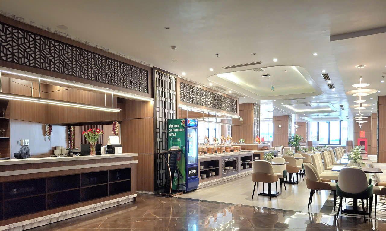 A modern hotel lobby with a reception desk, seating area, and vending machines.