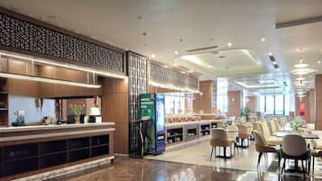 A modern hotel lobby with a reception desk, seating area, and vending machines.