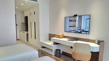 A hotel room with two beds, a desk, a chair, a TV, and a wardrobe.