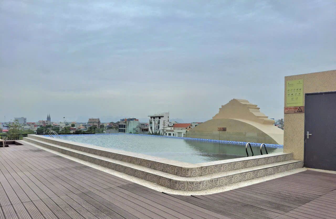 A rooftop pool with a view of the cityscape, a water feature, and a door with a sign.
