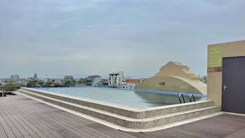 A rooftop pool with a view of the cityscape, a water feature, and a door with a sign.