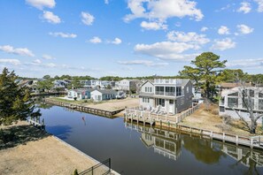 A waterfront property with a dock, a large house with a balcony, and a smaller building. - 5 Bedroom Bayside Beach House! (South Bethany)