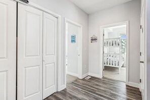 Un pasillo con puertas blancas, piso de madera y un armario con contenedores de almacenamiento estampados.