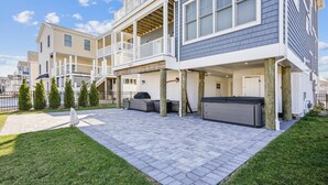 Edificio residencial de dos pisos con un patio cubierto que incluye mobiliario exterior y una parrilla.