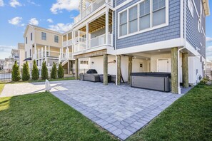 A two-story residential building with a covered patio area featuring outdoor furniture and a grill.