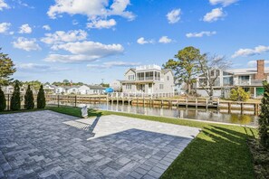 A waterfront property with a paved patio, a small dock, and a canal.