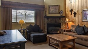 Una sala de estar acogedora con chimenea, un sofá, una mesa de centro y una lámpara.