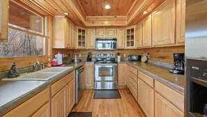 Una cocina con armarios de madera, electrodomésticos de acero inoxidable y un ventanal amplio.