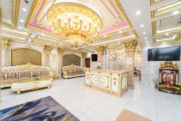 A luxurious interior with a grand chandelier, ornate gold detailing, a plush sofa, a marble reception desk, and a television. - Townhouse Cuong Thanh 3 Hotel (Ho Chi Minh City)