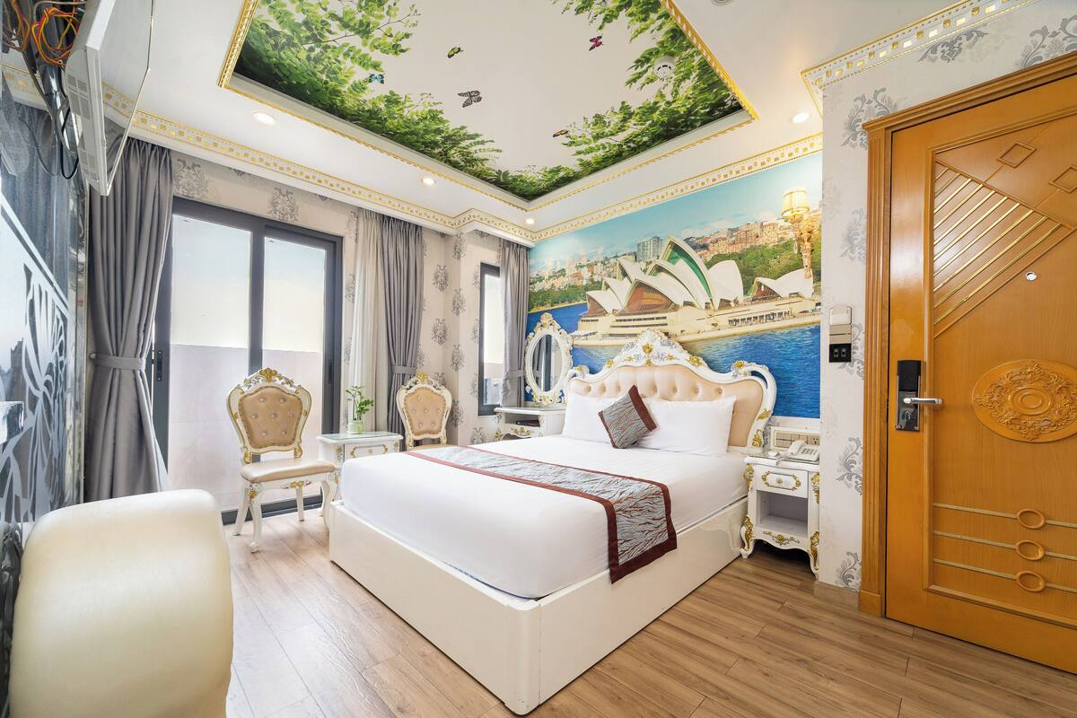 Ein luxuriöses Hotelzimmer mit einem großen Bett, aufwendigen Möbeln, einem Wandgemälde einer Stadtansicht und einer Holztür.