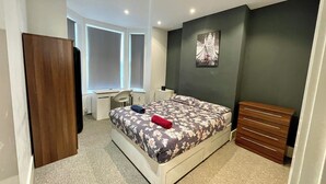 Un dormitorio con una cama, un escritorio y un aparador.