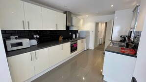 Una cocina moderna con armarios blancos, encimera negra y refrigerador de acero inoxidable.