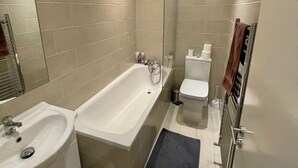 Un baño moderno con bañera, lavamanos e inodoro.