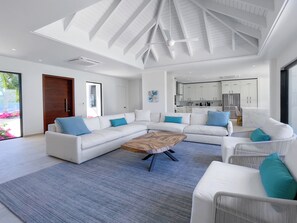 Relax in this stylish living room with a white sectional sofa, wooden coffee table, and geometric ceiling design.