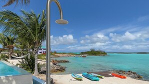 Zona de piscina frente a la playa, con ducha, kayaks y vistas al océano.