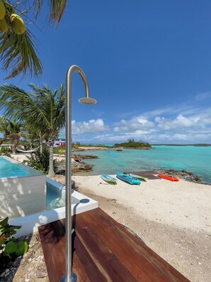 Enjoy a serene beachfront setting with a clear view of the ocean, a showerhead on the deck, and access to a swimming pool and kayaks for water sports.