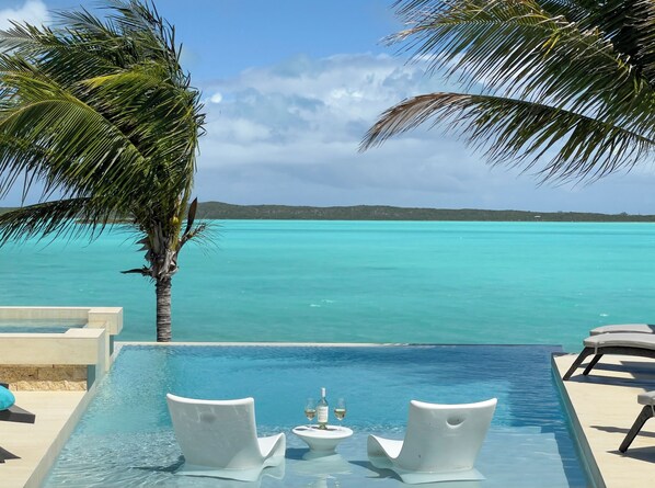 Relax by the serene infinity pool overlooking the turquoise sea and distant islands.