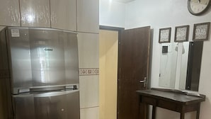 Una cocina con un refrigerador de acero inoxidable, una mesa de madera y un reloj en la pared.