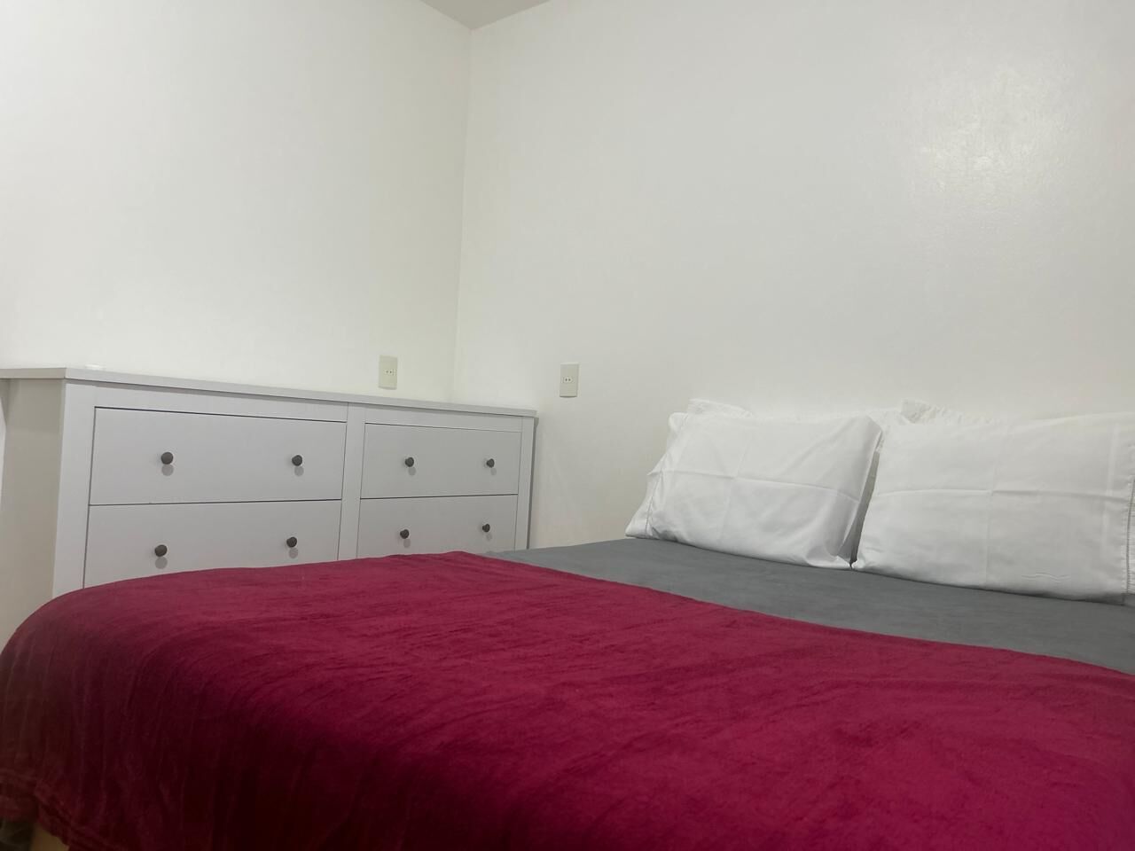 Ein Schlafzimmer mit einem Bett, einem weißen Schminktisch und zwei weißen Kissen.