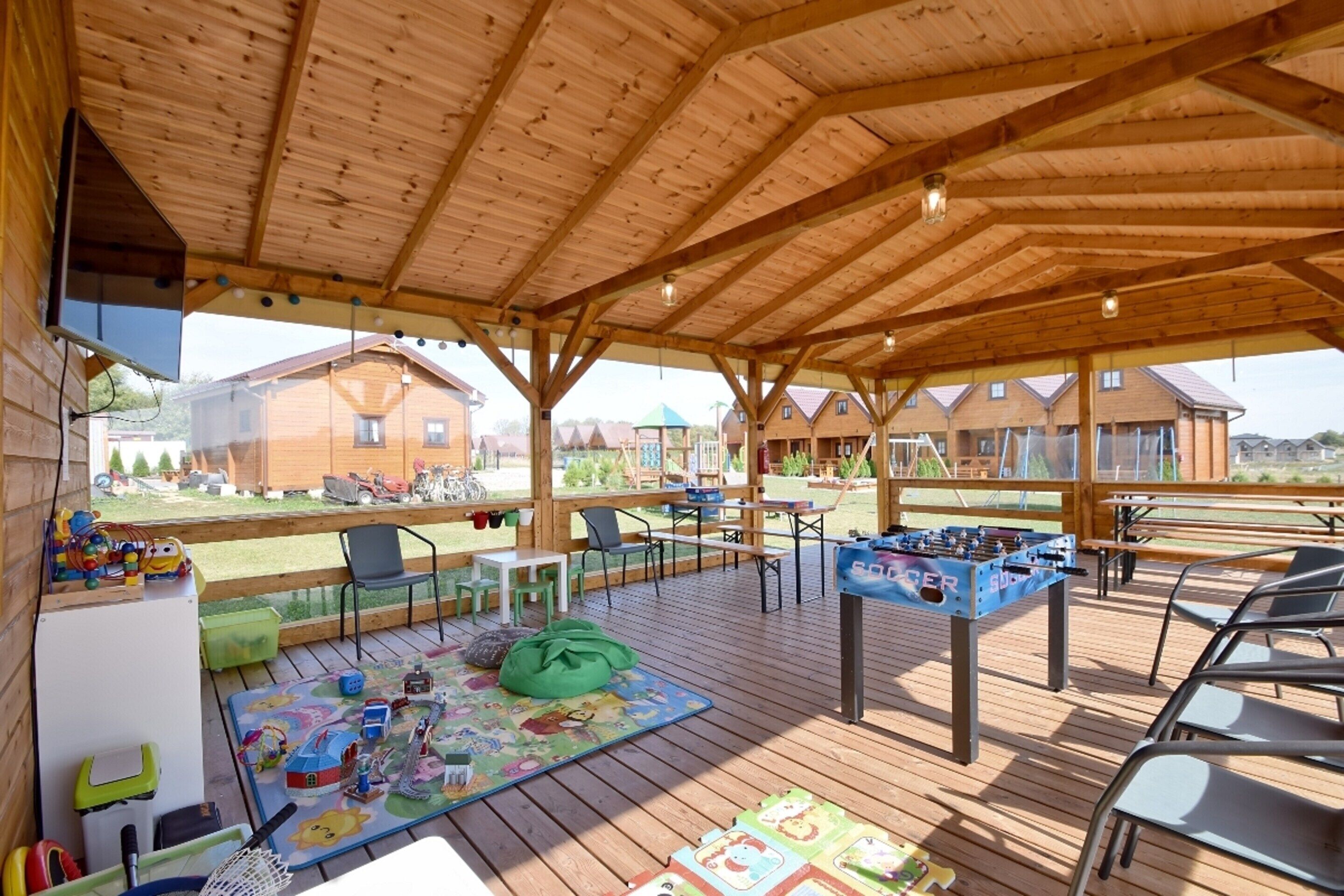 Un espace extérieur abrité doté d’un plancher en bois, de sièges et d’une table de baby-foot.