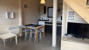 Un interior de madera con una mesa de comedor, sillas, una zona de cocina y una chimenea.