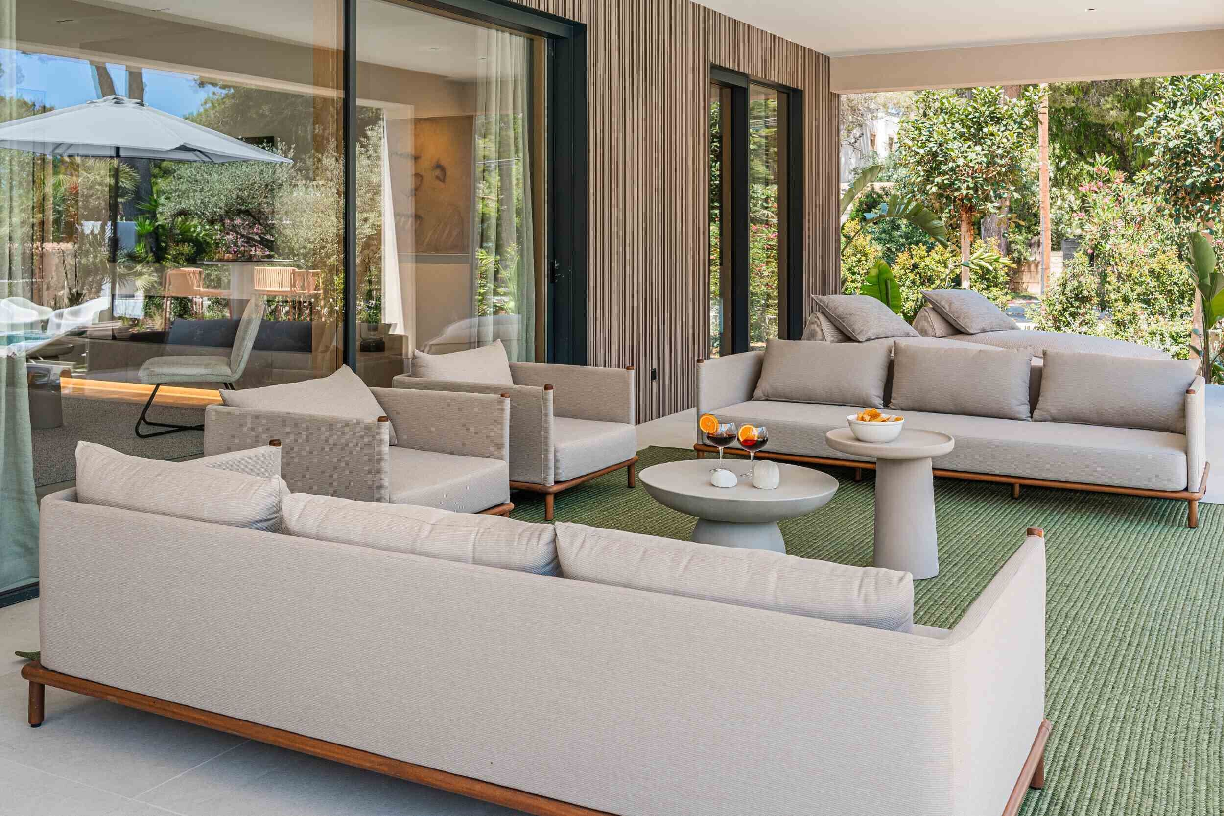 A modern living room with a sofa set, a coffee table, and a glass door leading to a balcony with outdoor furniture.