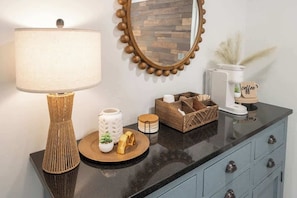 A kitchen counter with a lamp, a mirror, and various kitchen items.