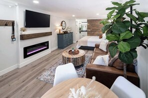 A modern living room with a fireplace, a television, a large plant, and a sofa.