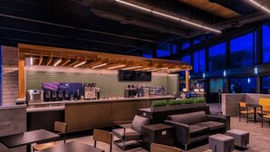 Un espace de détente moderne comprenant des sièges, un bar et un écran de télévision.