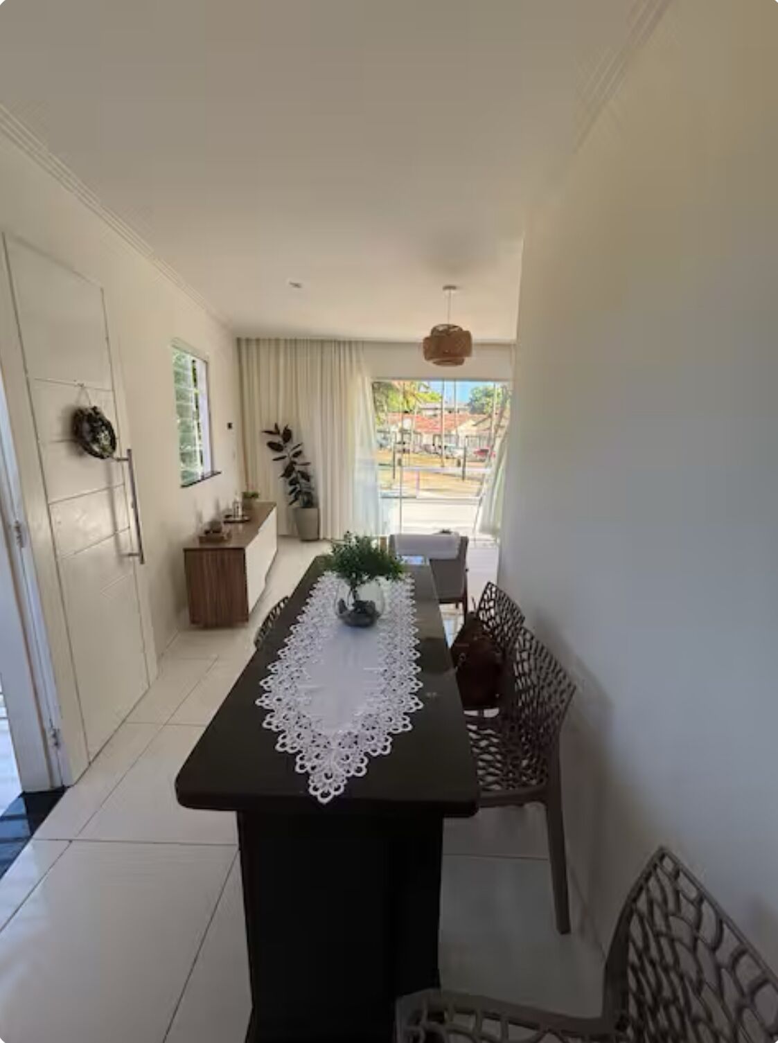 Ein schmaler Flur mit einem für zwei Personen gedecktem Esstisch, einem Blumentopf und Blick ins Freie.