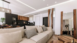 Una sala de estar moderna con un sofá, detalles de madera y un comedor.