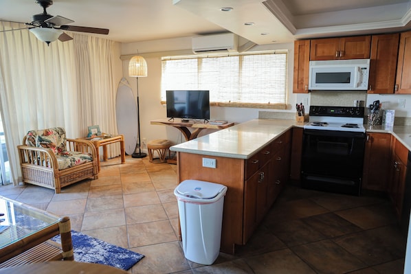Una cocina compacta con microondas, estufa y un pequeño comedor con mesa y sillas.