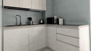 Een moderne keuken met witte kastjes, een zwart aanrecht en een marmeren vloer.