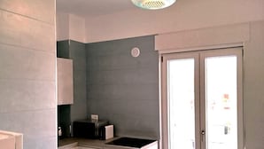 Een moderne keuken met een ingebouwde kookplaat, een eethoek met tafel en stoelen, en een bijzondere hanglamp.
