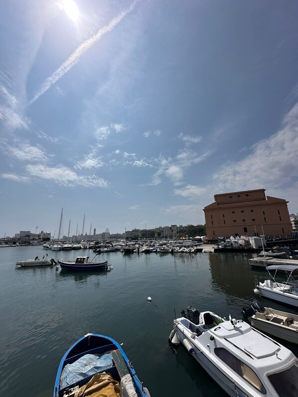 A marina with boats docked, a large building in the background, and a clear sky. - LUXURY MELO APARTMENT (Bari)