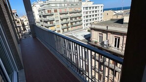 Een balkon met uitzicht op een stadsgezicht, met meerhoog bouwwerken en een helderblauwe lucht.