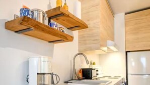 A modern kitchen with wooden cabinets, a built-in oven, a coffee maker, and a sink. - L'Agachoun - Ski & Bike 2mns from Mont St-Anne! (Saint-Ferréol-les-Neiges)