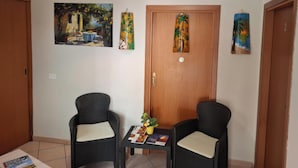 Ein Zimmer mit zwei Korbstühlen, einem kleinen Tisch mit einer Zeitschrift und drei Bildern an der Wand.